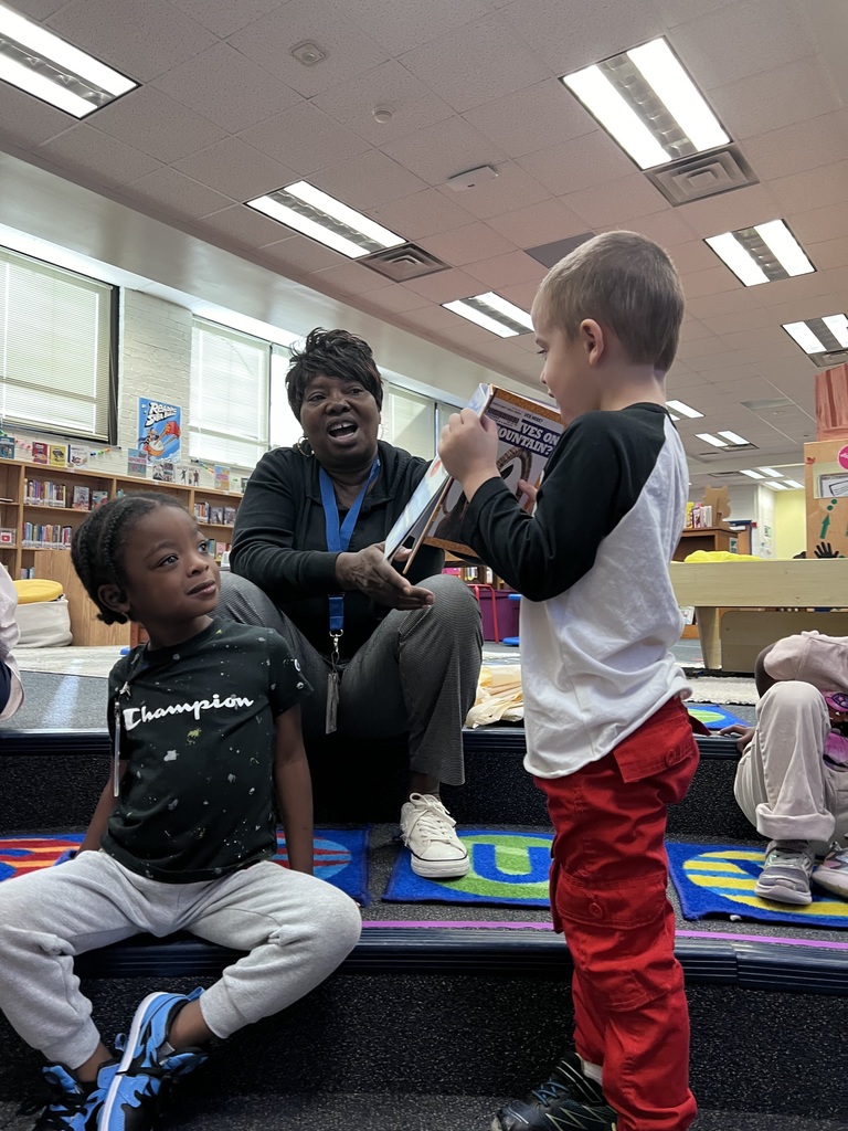 A preschooler shows his nonfiction book to his classmates.