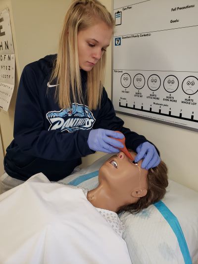 Student practicing eye irrigation on manikin.