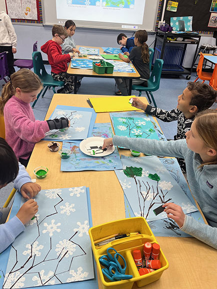 two tables of fourth grade students working on their art