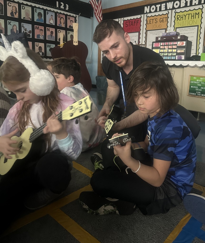 two third grade students strumming ukuleles