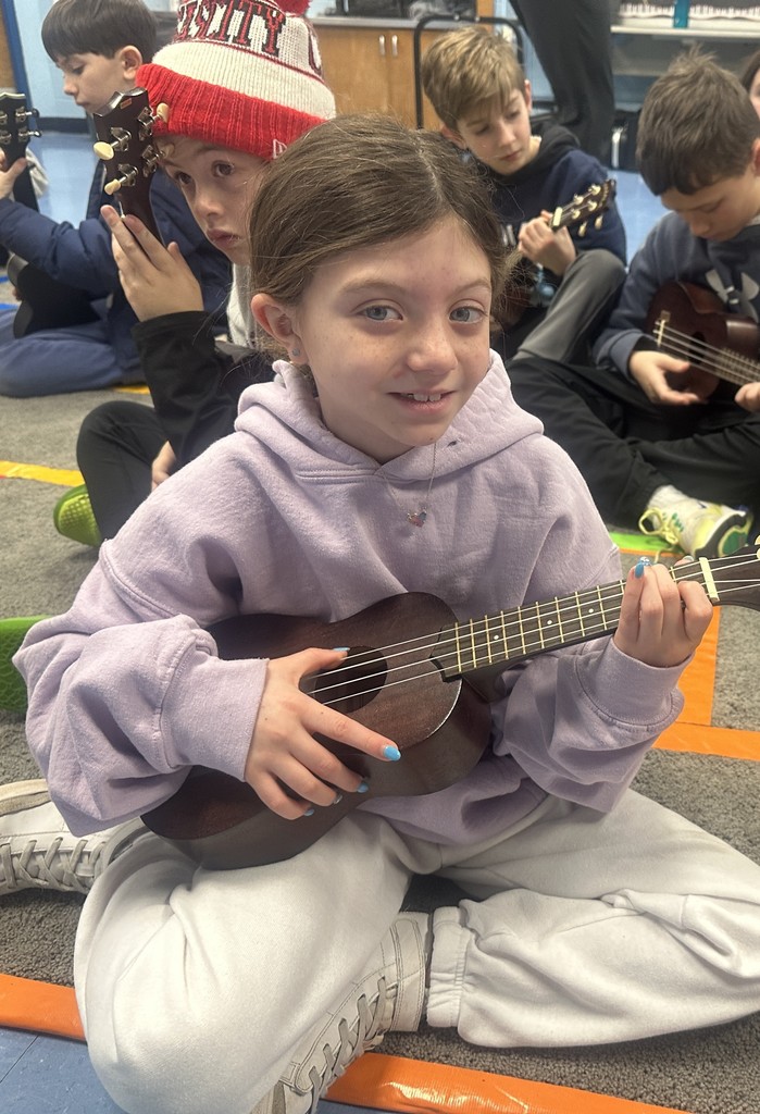 third grade student strumming ukulele
