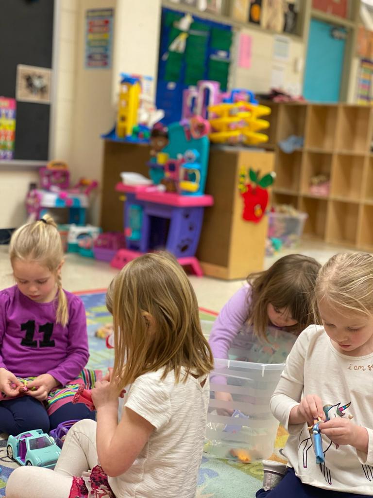 Group of girls playing with dolls on the ground.