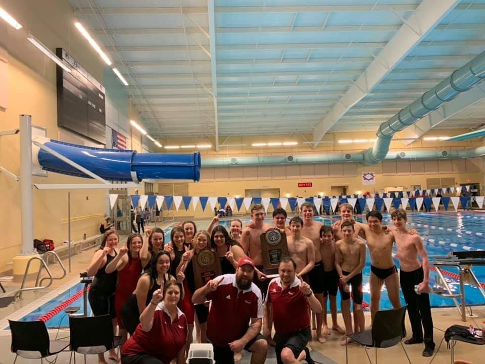 Swim team posing with trophy