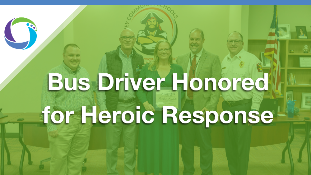 Five individuals pose together with a framed certificate for an award ceremony. Text reads: "Bus Driver Honored for Heroic Response.