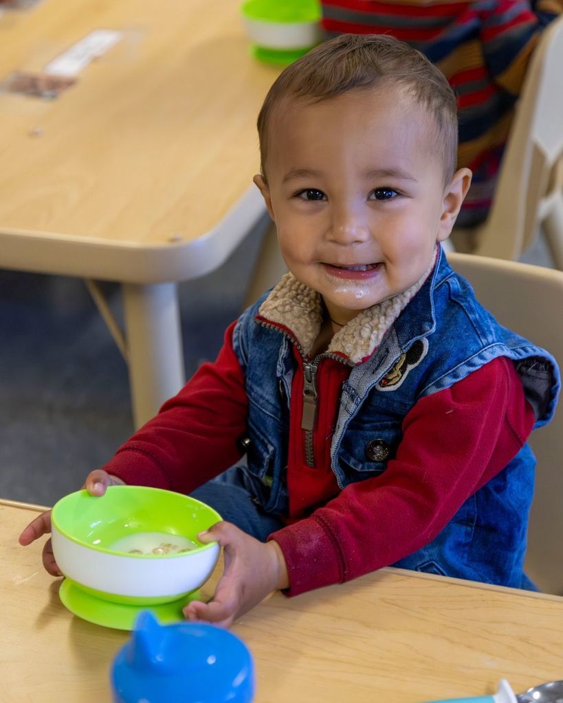 Little boy smiling and eating cheerios.