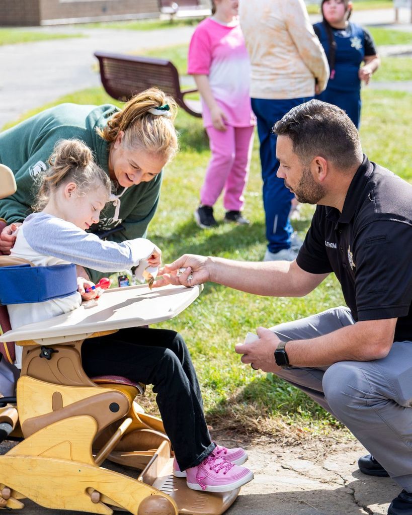 Deputy Thompson giving student a sheriff badge sticker.
