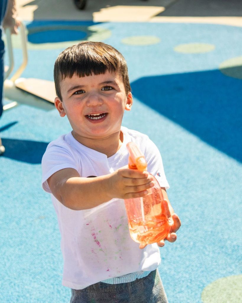 Child spraying water at the camera