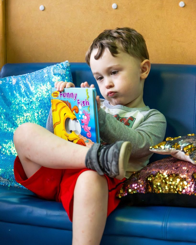Child sitting on a couch and reading a book