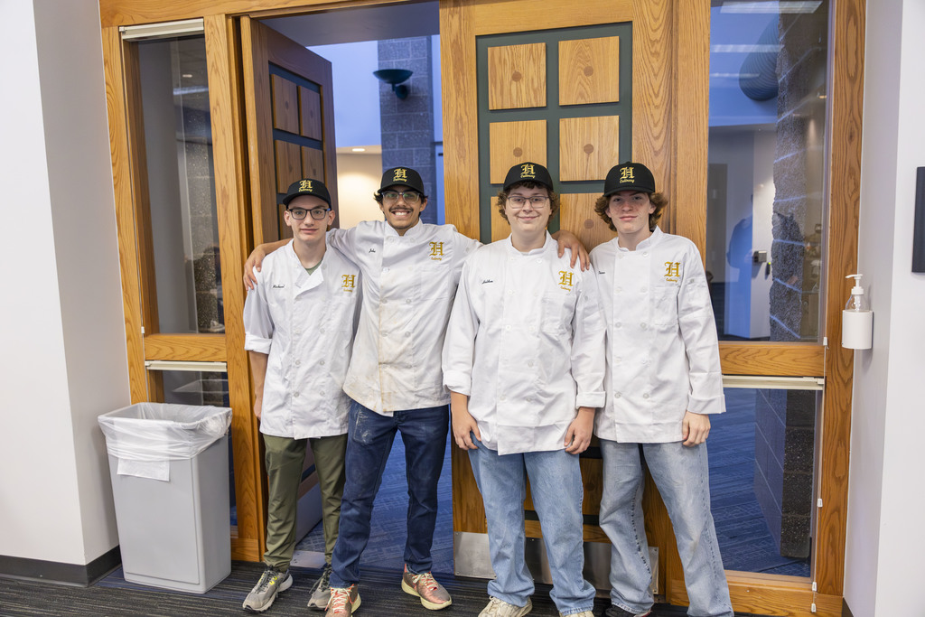 Kids in chef coats smiling for the camera. 