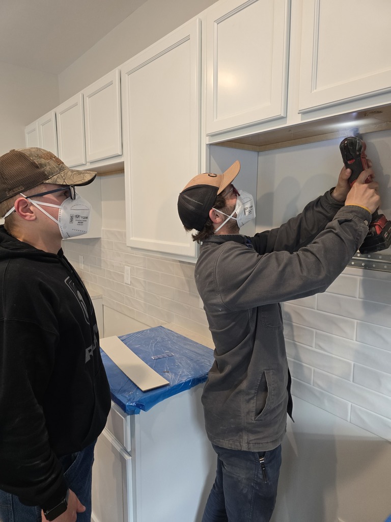 Student watches builder hang cabinets