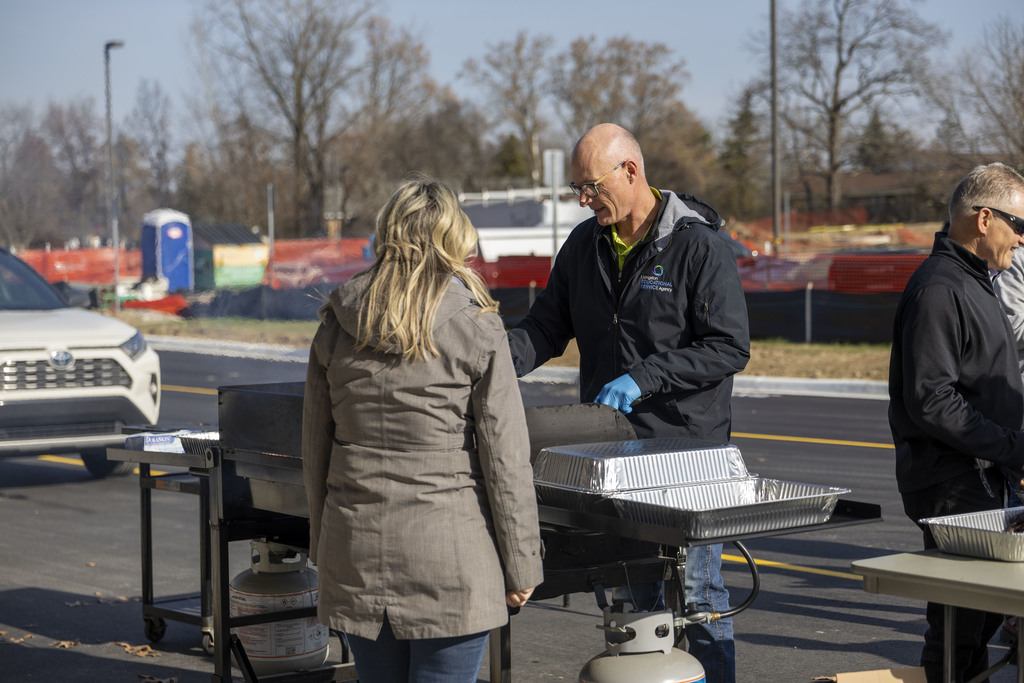 Man cooking at the grill and serving a lady.