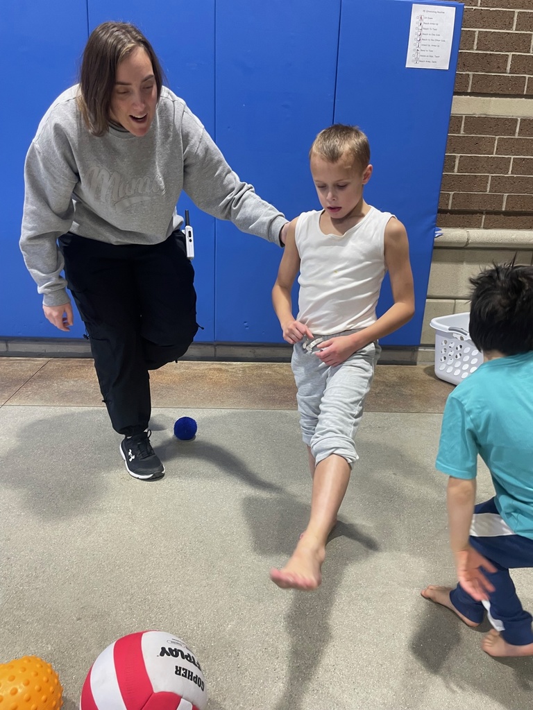 Assistant helping student kick a ball.