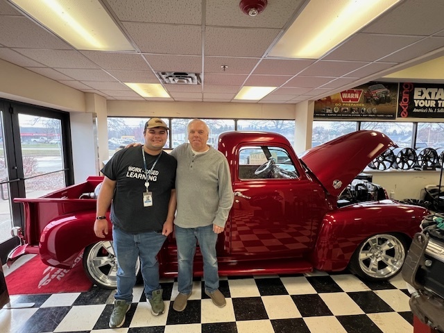 Learner Aiden with Mike Owner of Diversified standing in front of showroom truck 