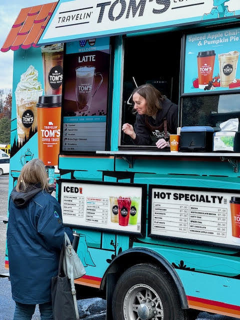 Blue Food truck with a women in the window and a women ordering