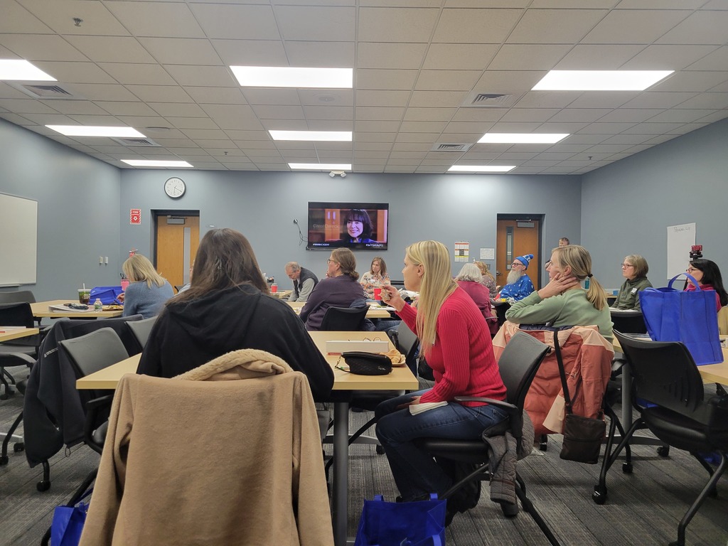 Group of  adults sitting in a conference room.