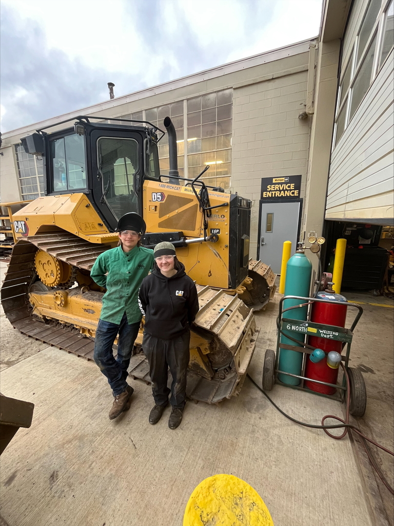 Student and worker standing by heavy equipment