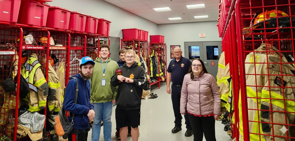 A group of learners and a fireman standing inside a fire department.
