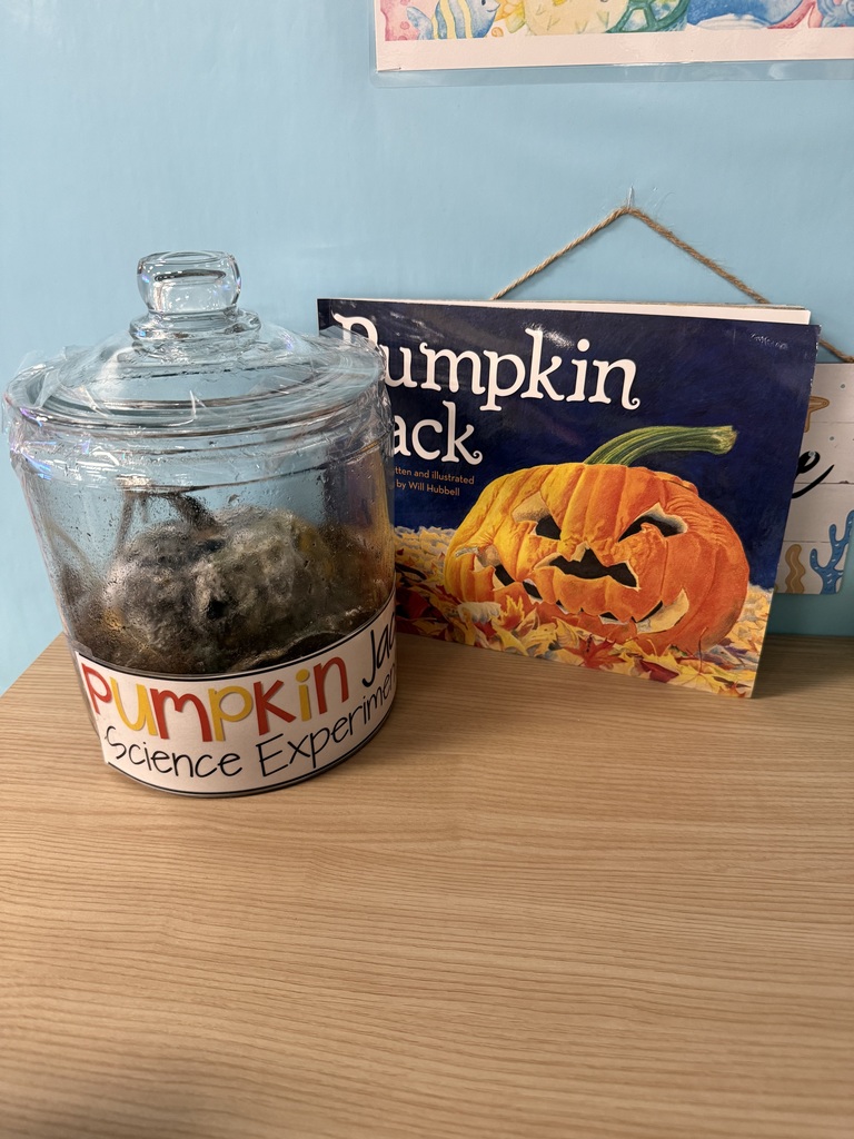 A glass jar containing a decomposing pumpkin is displayed next to the children’s book Pumpkin Jack.