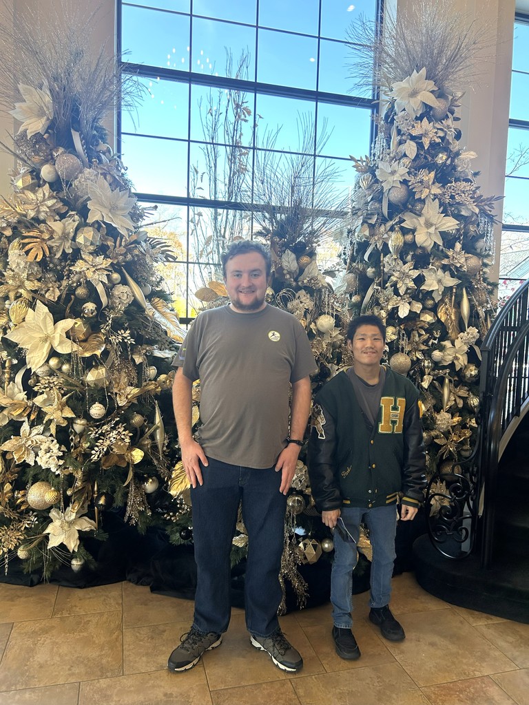 2 men standing in front of holiday trees