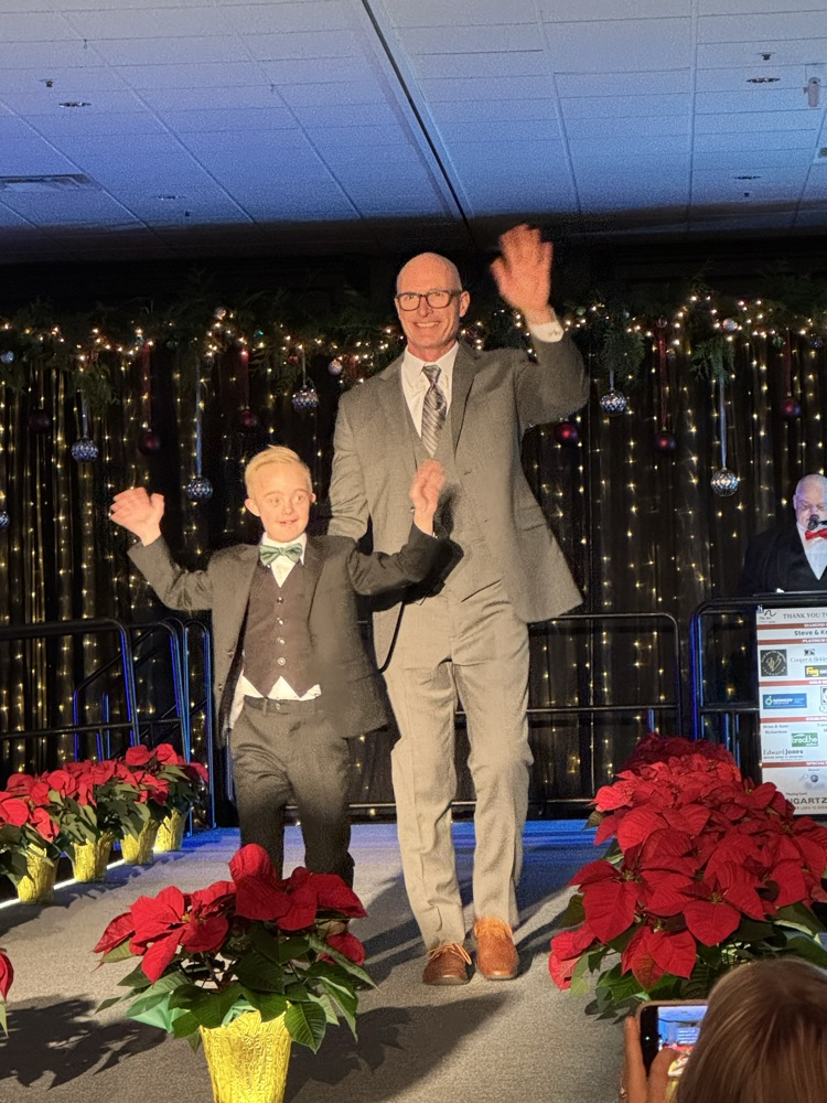 Two men standing and waving at audiences