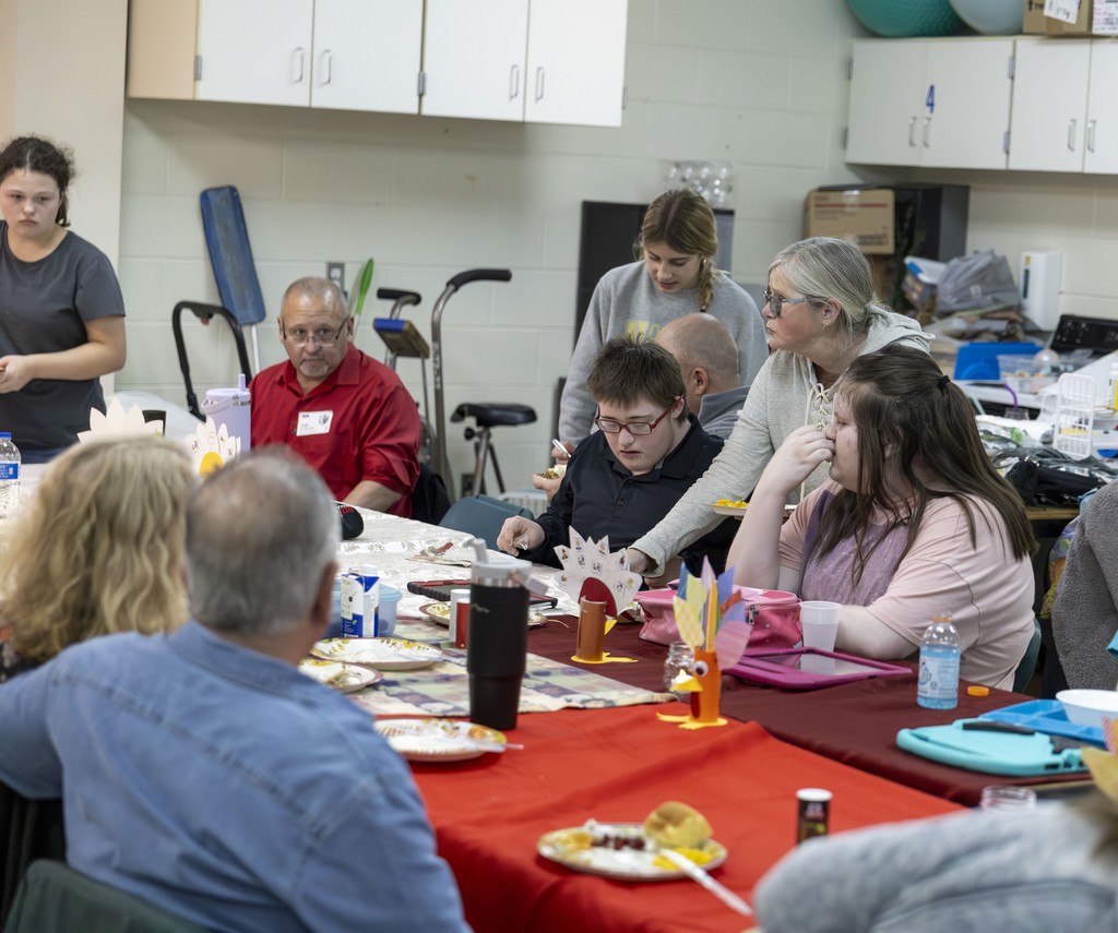 Students, families, and staff sitting around a large table, sharing a meal.