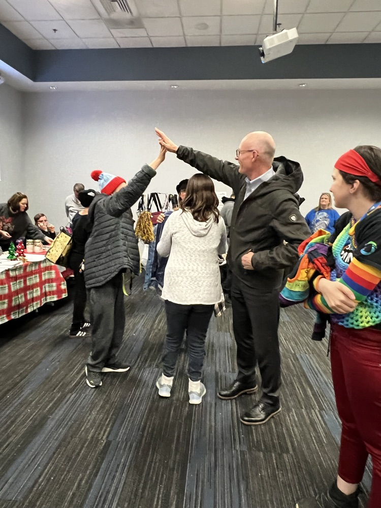 Two people in large rooms give each other high fives