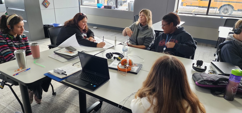 Female adults sitting around a couple of tables, having a discussion.