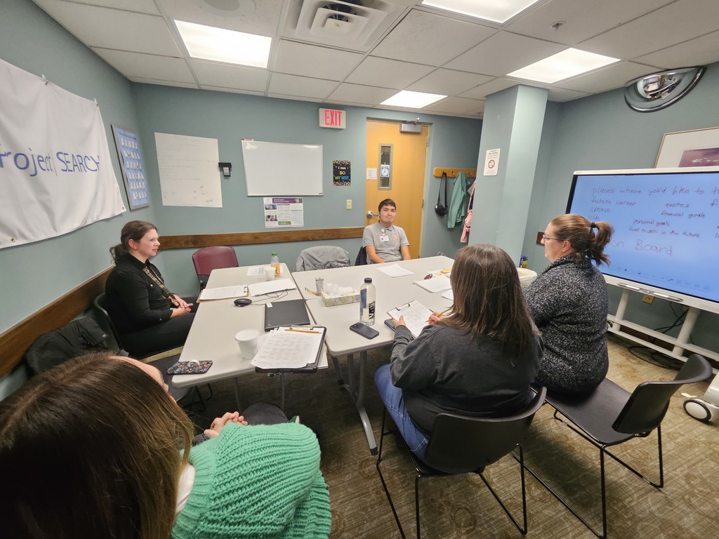 Group of people sitting around a table in a classroom