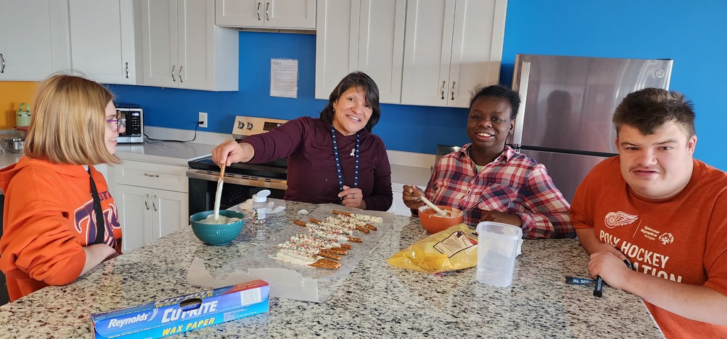 A teacher and adult learners standing are a kitchen island making decorative pretzels..