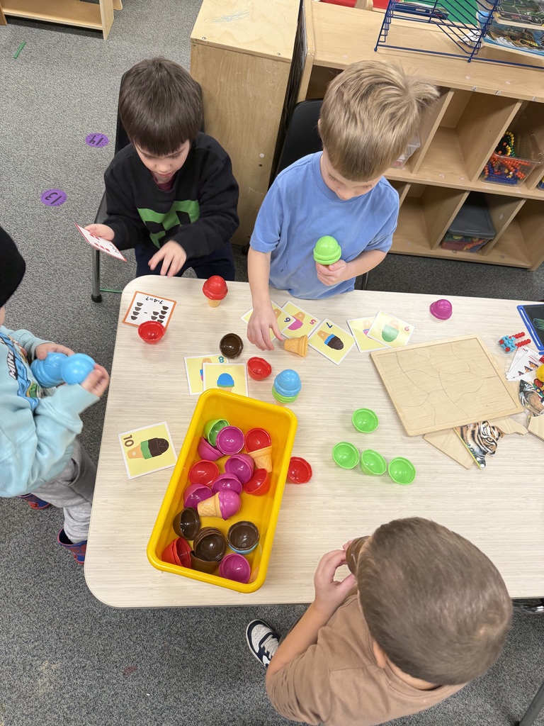Children gather around a table matching ice cream scoops and cones to number cards.