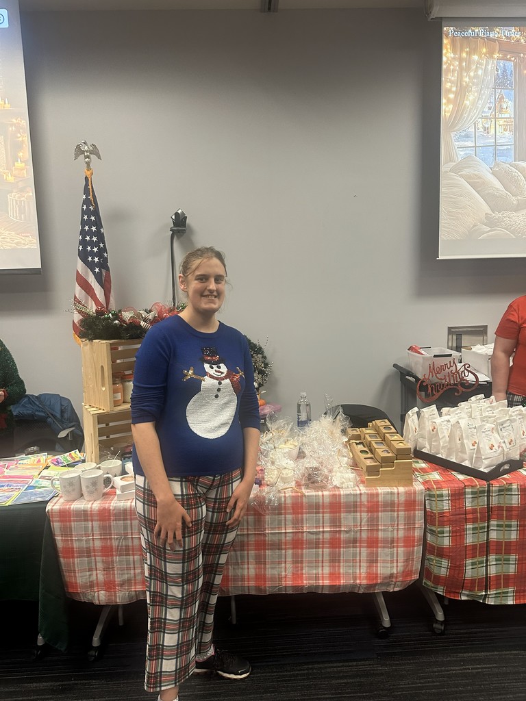 Female standing in front of a table of crafts.