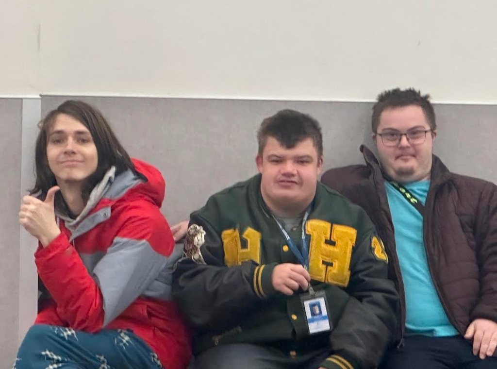 Three young adults sitting on a bench.