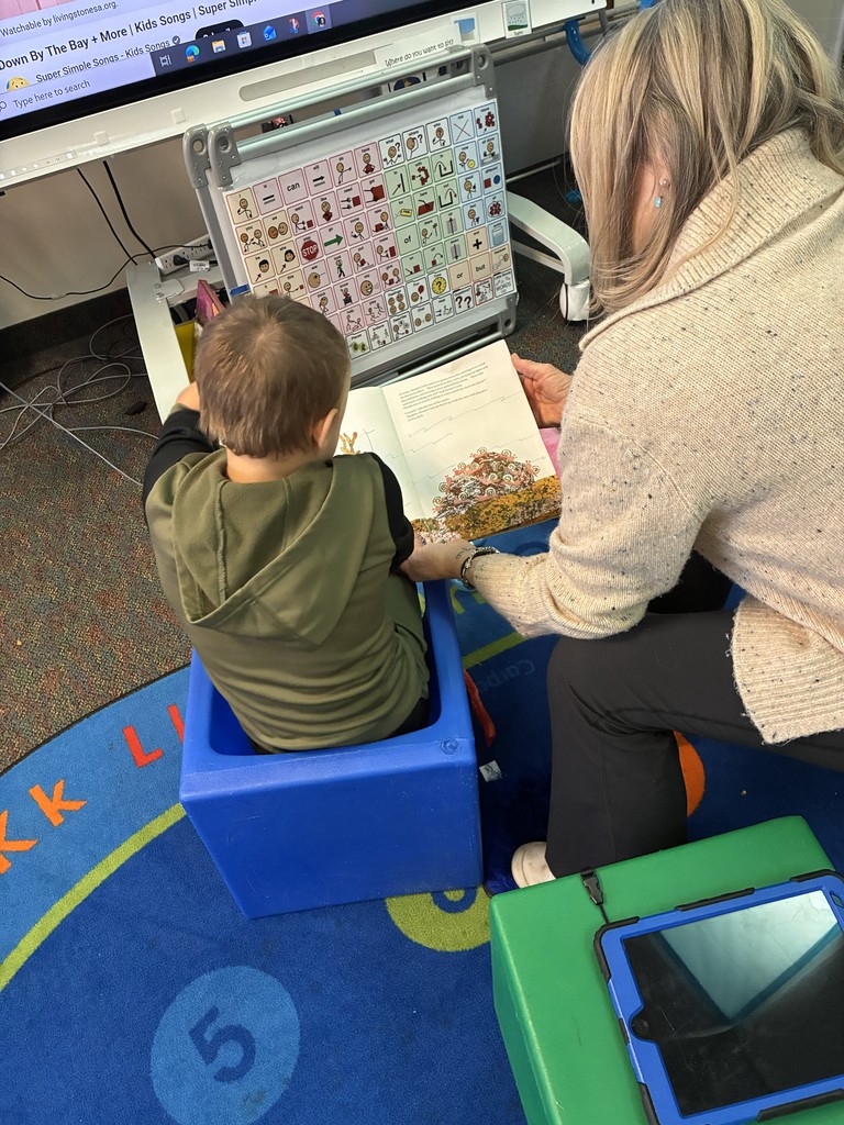Student and assistant sitting with a book and a core board.