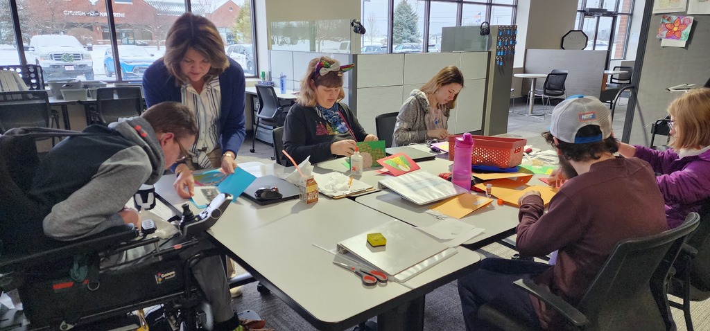 A teacher and learners sitting around a table making cards.