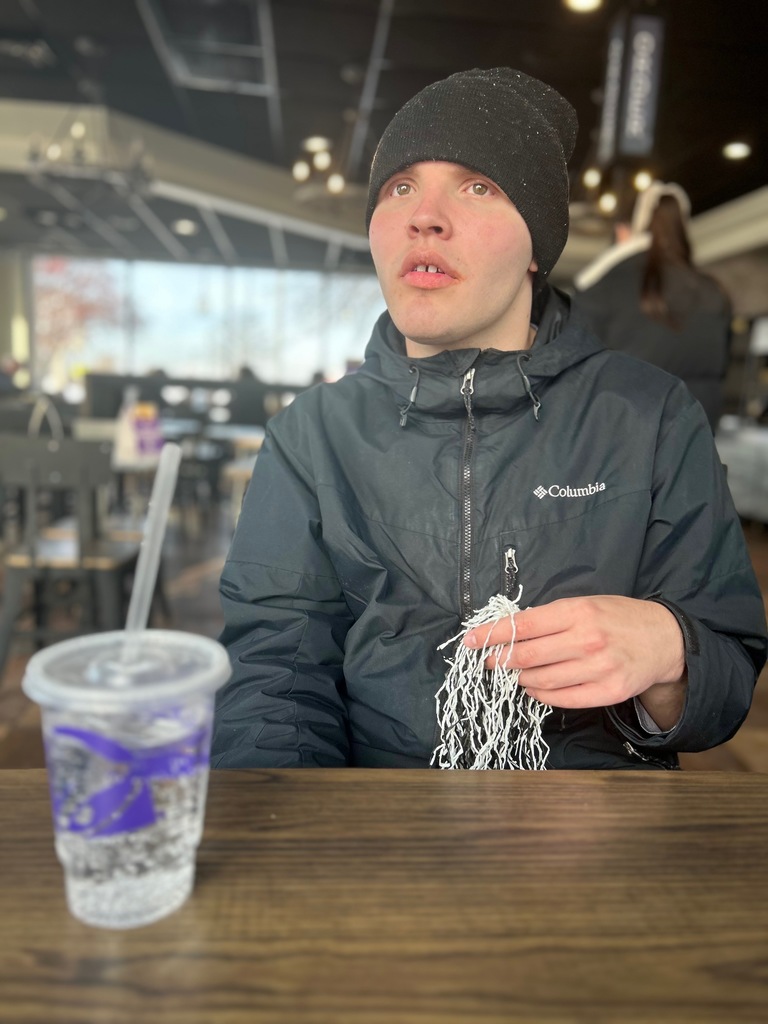 Student sitting at table drinking pop from Taco Bell