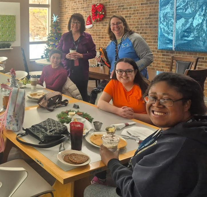 A group of smiling, female adults  around a table.