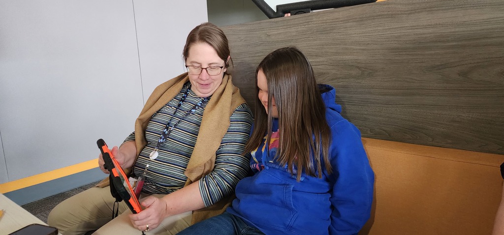 Two females sitting next to each other using an IPad.
