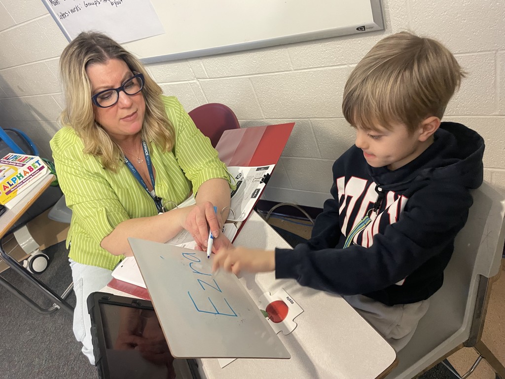 Adult showing students a dry erase board with their name written.