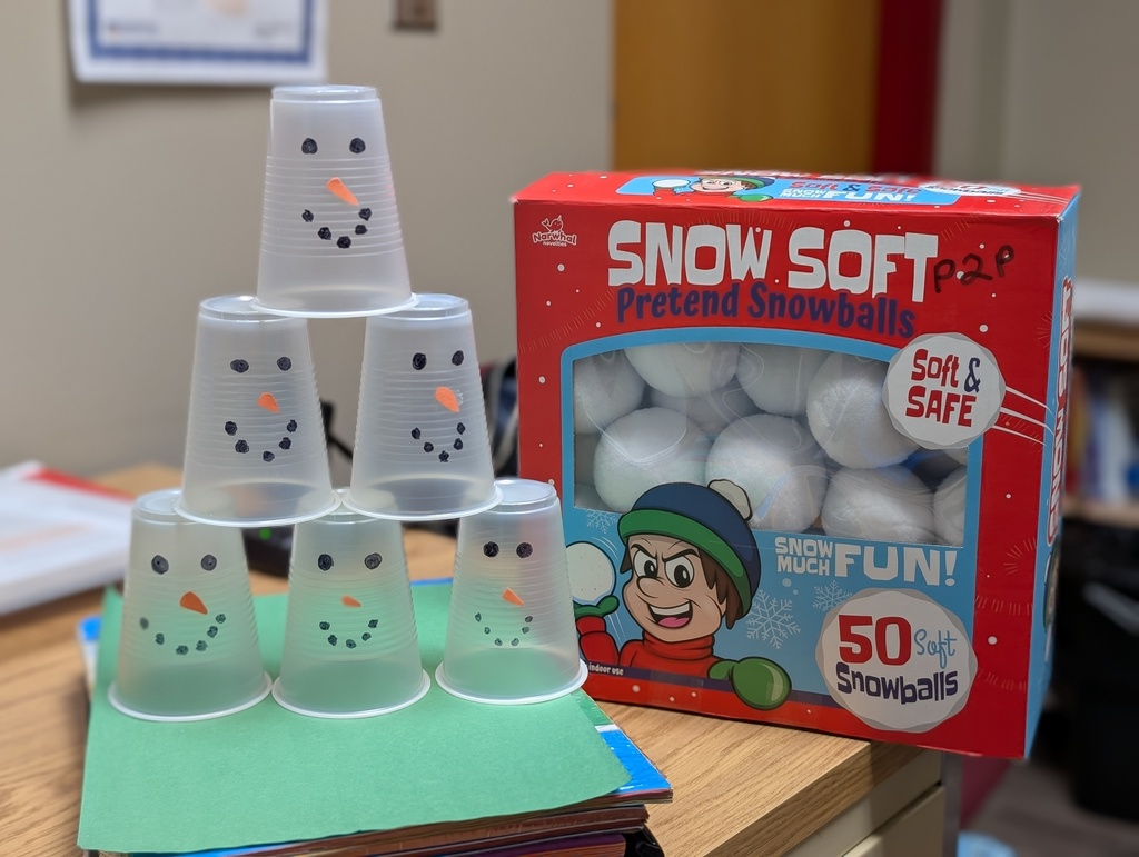 Cups with snowman faces stacked into a pyramid next to a box of pretend snowballs.
