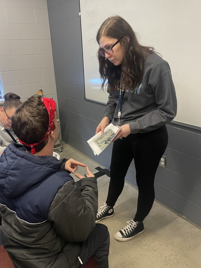 Teacher showing a student a page from a book.