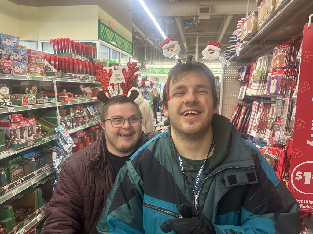 Two young men smiling, while standing in an isle of a store.