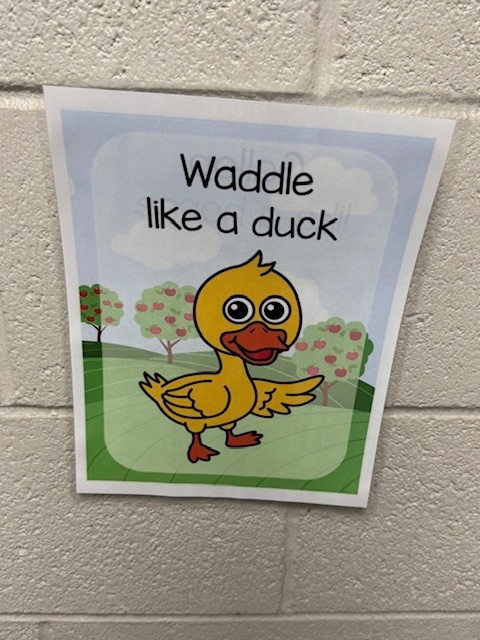 A hallway poster of a cartoon duck reading “Waddle like a duck."