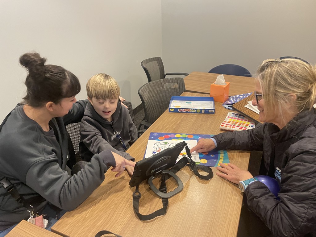 Student sitting at a table with two adults.