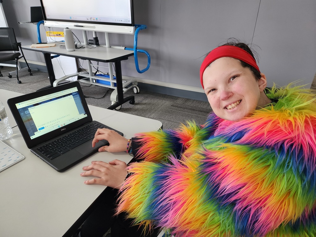 A young lady in a colorful jacket, creating an email.