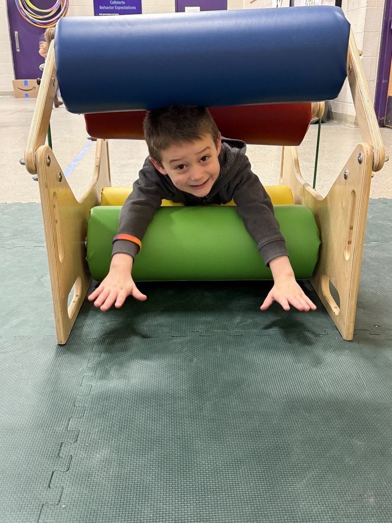 Preschooler crawling through a padded tunnel, reaching forward while practicing balance, coordination, and upper body strength.