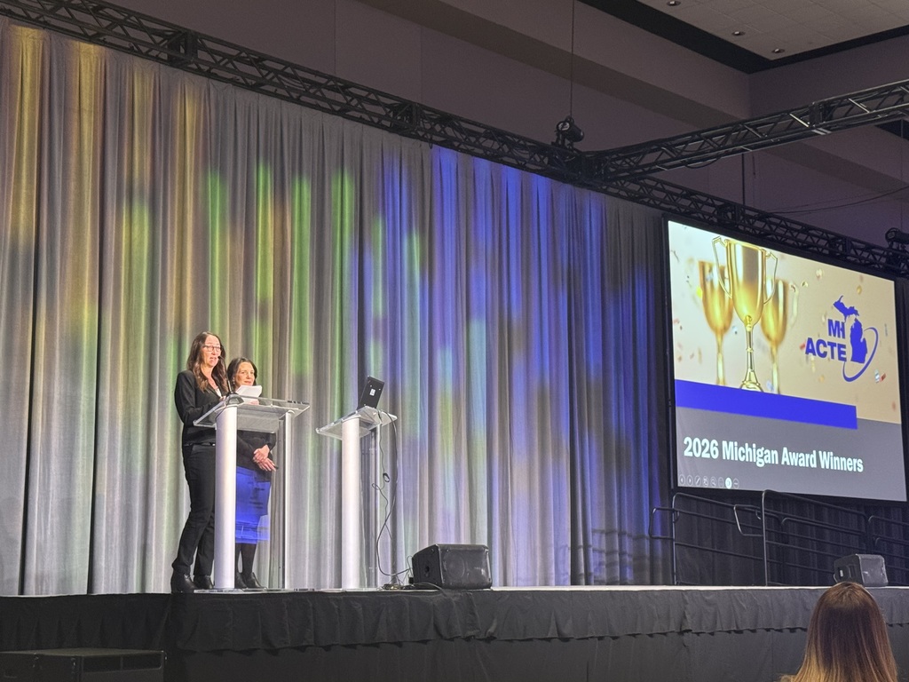 Two woman standing on a stage in front of a podium. 