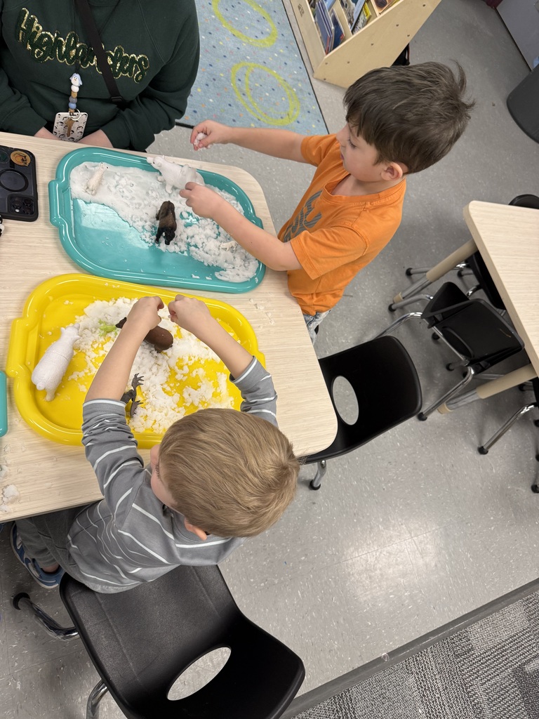 Preschool children explore artificial snow at tables, playing with winter animals and vehicles during a hands-on sensory activity.