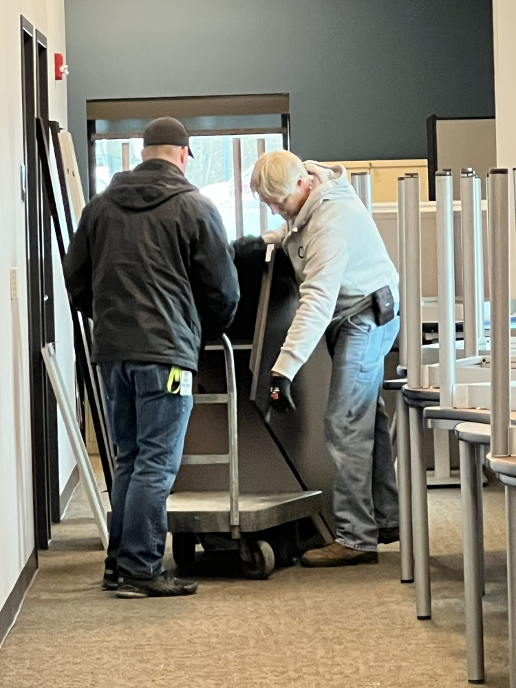 Two men loading a hand cart with a desk