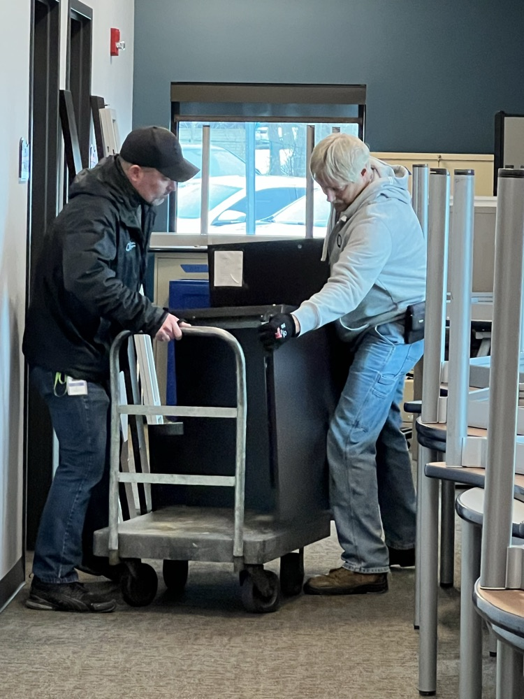 Two men with a loaded hand cart.