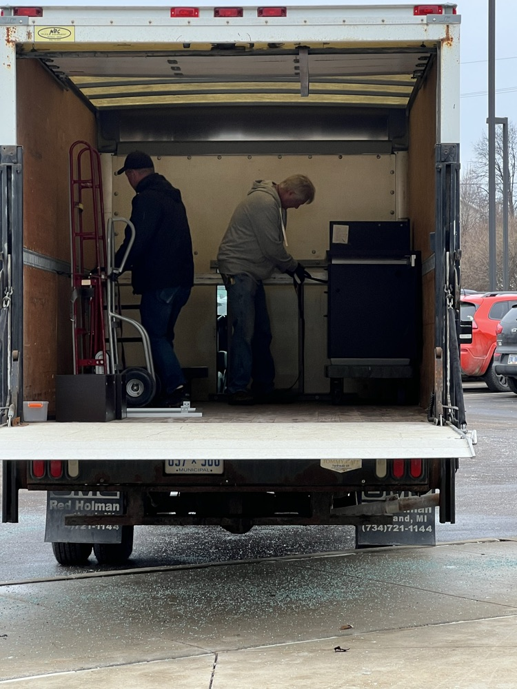 Two men secure a desk inside a box truck